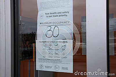 View of sign Mask Required, Maximum Occupancy 30 people at the entrance of Store due to COVID-19 Prevention. Pandemic Building Editorial Stock Photo