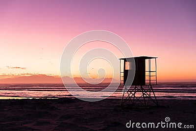 View of silhouette lifeguard hut on sandy beach against sea and purple sky, copy space Stock Photo