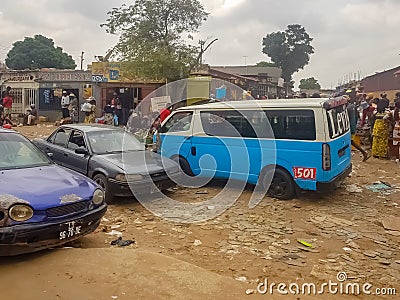 View of slum with a exterior market in the Luanda city downtown center with clay road, people, vehicles and buildings Editorial Stock Photo