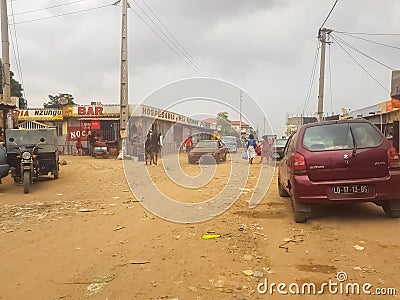 View of slum in the Luanda city downtown center with clay road, people, vehicles and buildings Editorial Stock Photo