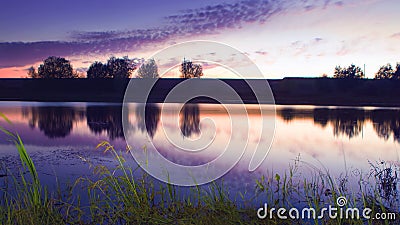 View of a small countryside pond in early still and warm summer night phot Stock Photo