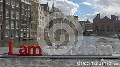 View of small plastic figure of Iamsterdam letters sculpture on the bridge against blurred cityscape, Amsterdam Editorial Stock Photo