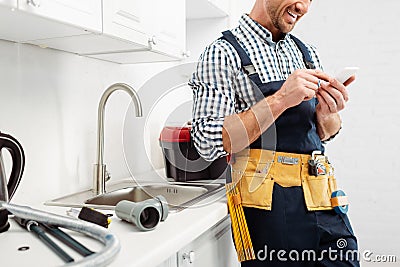 View of smiling plumber using smartphone Stock Photo