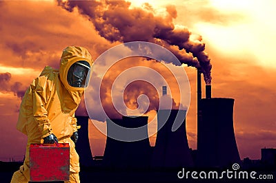 View of smoking coal power plant at sunset and men in protective hazmat suit Stock Photo