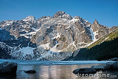 view of snow covered mountain peaks over lake water, Morskie Oko, Sea Eye, Tatra National Stock Photo