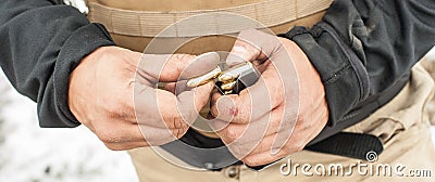 View of soldier hands load gun bullets into cartridge clip Stock Photo