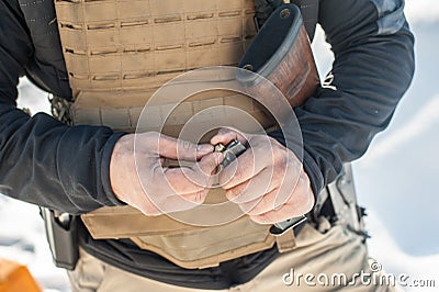 View of soldier hands load gun bullets into cartridge clip Stock Photo