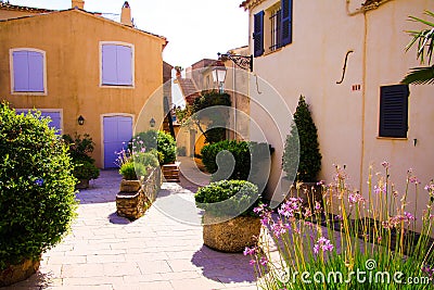 View on square of mediterranean village decorated with pots of flowers and green plants in bright sunshine - Gassin, Cote dÂ´Azur Stock Photo