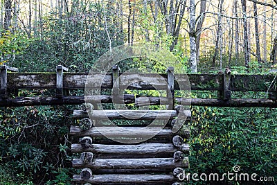 View of a stacked log support for a water sluice, autumn leaves and rhododendrons Stock Photo