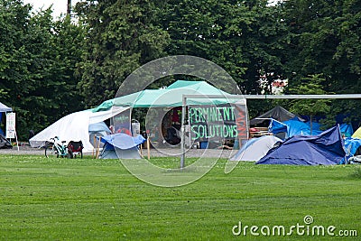 View of Strathcona Park in downtown Vancouver full of tents and homeless people with sign `Permanent solutions now` in the backgro Editorial Stock Photo