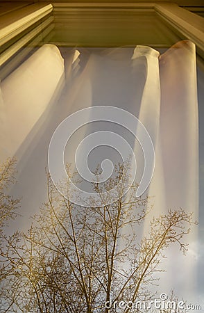 View of the street through the window, which reflects the curtains, illuminated by the sun. Stock Photo