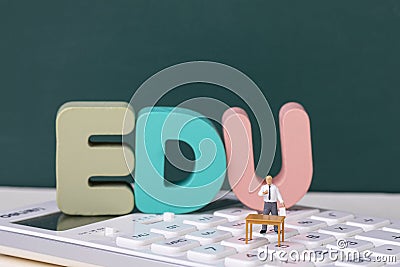 View of teacher figurine standing on a calculator around EDU letters Stock Photo