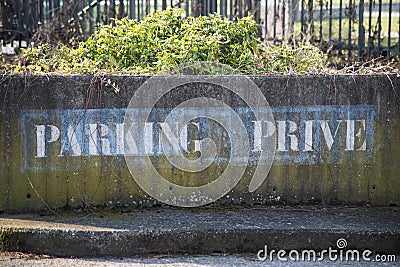 text on stoned wal in french : parking prive, traduction in english, private parking Stock Photo