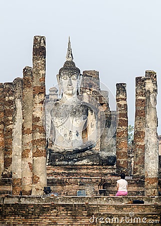Thai woman praying in front of a big seated Buddha statue, Sukhothai, Thailand Editorial Stock Photo