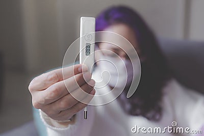 thermometer in the foreground held by a woman in the background Stock Photo