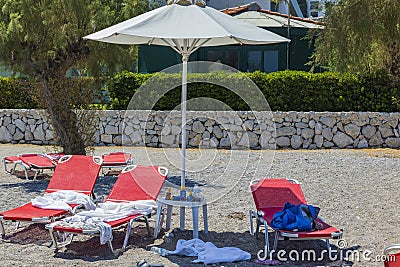 View of things and shoes of tourists left on sun loungers on beach. Greece. . Stock Photo