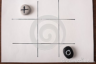 View of tic tac toe game with stones marked with naught and cross on white surface Stock Photo