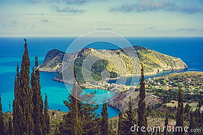 View to Assos village in sun light and beautiful blue sea. Cypress trees in foreground. Kefalonia island, Greece Stock Photo