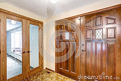 View to brown wooden enterance door. Tile floor and carpet floor in the next room. Stock Photo
