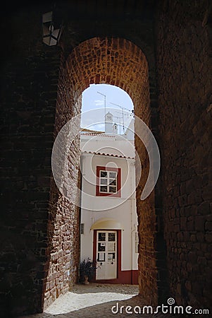 View to the street with historical building trough an arch in Silves, Portugal. Editorial Stock Photo