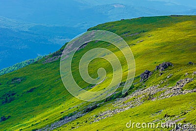 View in to the valley from the top of a mountain. huge rocks on the grassy hillside. clouds on the sky. beautiful sunny weather Stock Photo