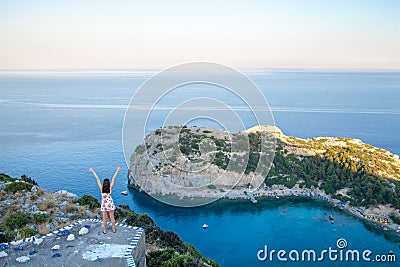 View from top on Anthony Quinn Bay and beach, Rhodes in Faliraki, Greece. Happy girl Raising One Hand. Beautiful beach and bay on Editorial Stock Photo