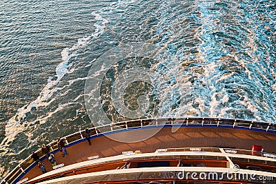 View from the top at the back deck of the cruise ship, leaving foamy trace on the water and waves in the ocean during sunset. Editorial Stock Photo