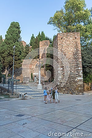 View at the tourist people visiting and strolling on Malaga Alcazaba building entrance, fortress and pedestrian path crossing with Editorial Stock Photo