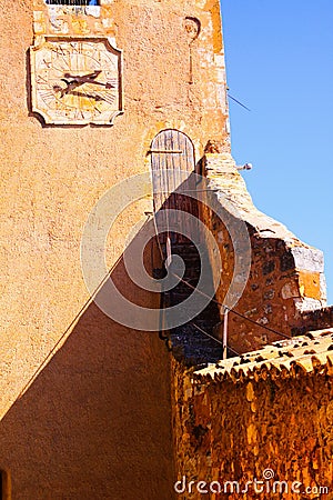 View on tower of fortress with clock and red ochre stone wall shadow with blue sky - Roussillon en Provence, France Editorial Stock Photo