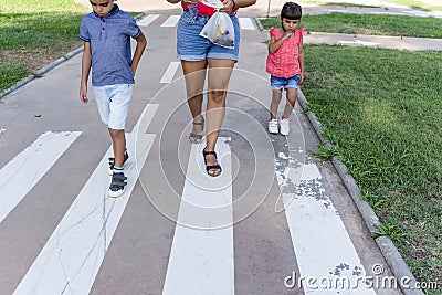 Two kids walking with their mother outdoors in a pathway in a park. Stock Photo