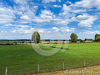 View on typical dutch rural flat landscape along river Maas with cycling track near Nijmegen, Netherlands Stock Photo