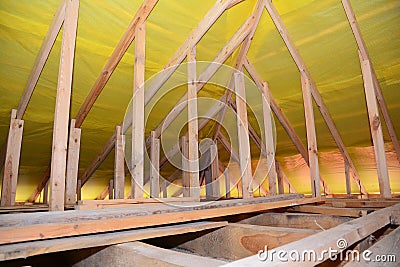 A view on unfinished attic from inside the house with a close-up on wooden ceiling joists, roof beams, rafters, wall studs and Stock Photo