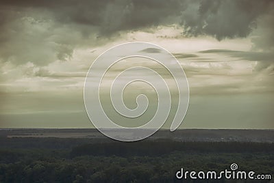 View of the valley covered with forest under the hazy cloudy sky Stock Photo