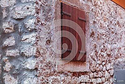 View of wall of coarse stone and close wooden window FOCUS ON C Stock Photo