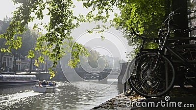 View of wheel bicycle on the Amsterdam amstel canal, next to floats tour boat, sunny european autumn Stock Photo