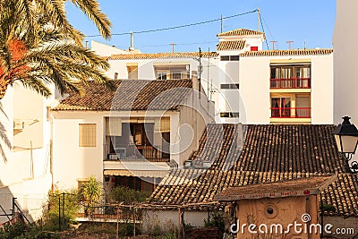 View of white houses with a tiled roof and balconies, and a palm tree in the old town of Altea, Spain on a hot sunny day Editorial Stock Photo