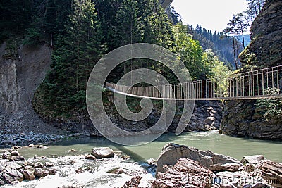View of a wild river in a gorge with a modern hanging bridge Stock Photo