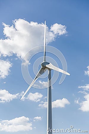 View of a wind turbine on top of mountains, cloudy sky as background Stock Photo