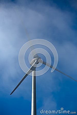 View of a wind turbine on top of mountains, fog on sky Stock Photo