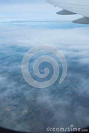 A view through the window of an airplane that sees the city, the fields, the sea and the clouds Stock Photo