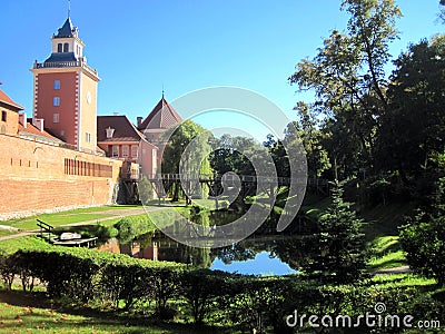 View of a wooden bridge over a moat with water, the spire of the town hall, a medieval castle with towers Stock Photo