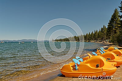 View of yellow paddle boats on the shore of Lake Tahoe. Stock Photo