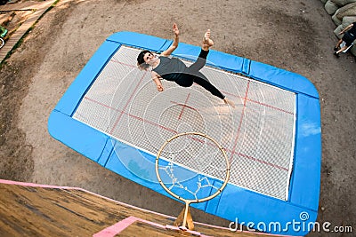 View of young cheerful woman jumping on trampoline. Stock Photo