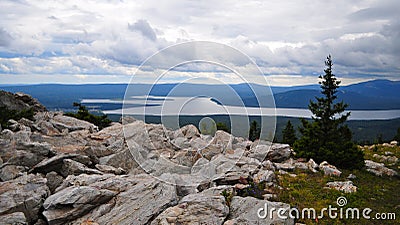 Zyuratkul Russia - July 2015 view of Zyuratkul lake from the top of Zyuratkul mountain in cloudy weather standing on stones Stock Photo