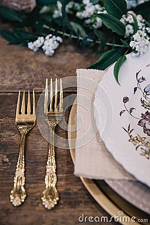 A vignette of a plate setting and gold vintage flatware from a table scape designed for a boho style event with rustic touches Stock Photo