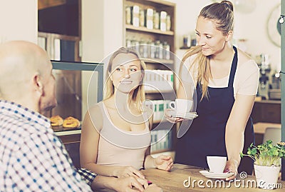 vigorous waiter girl brought cup of coffee for couple of different aged people Stock Photo