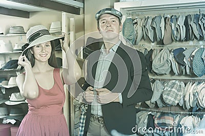 Vigorous young female and man choosing hats in the store Stock Photo