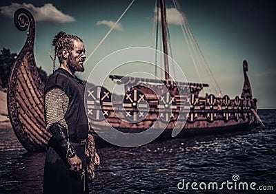 Viking warrior standing near Drakkar on seashore Stock Photo