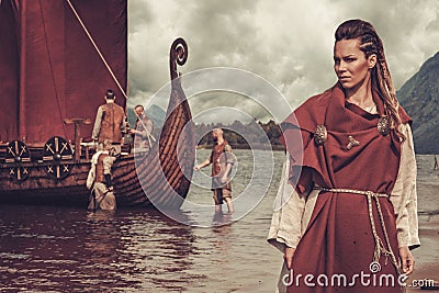 Viking woman standing near Drakkar on seashore Stock Photo