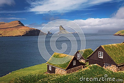 Village of Bour on Faroe Islands with Drangarnir sea stack in the background Stock Photo